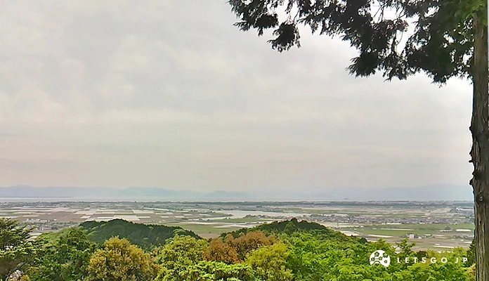 从安土城迹山顶眺望近江八幡平原与琵琶湖,前景为绿树山丘,远方湖面延伸至山脉