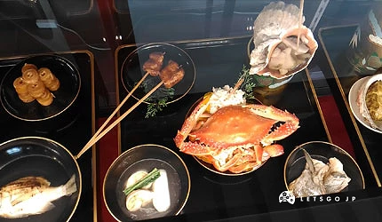 信长之馆内「安土晚宴」菜单模型,黑色漆器餐盘上摆放螃蟹、串烧等海鲜料理模型