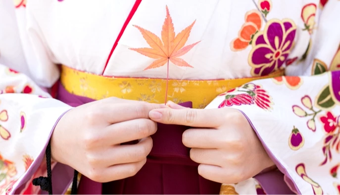 一個穿著和服的女生手拿楓葉