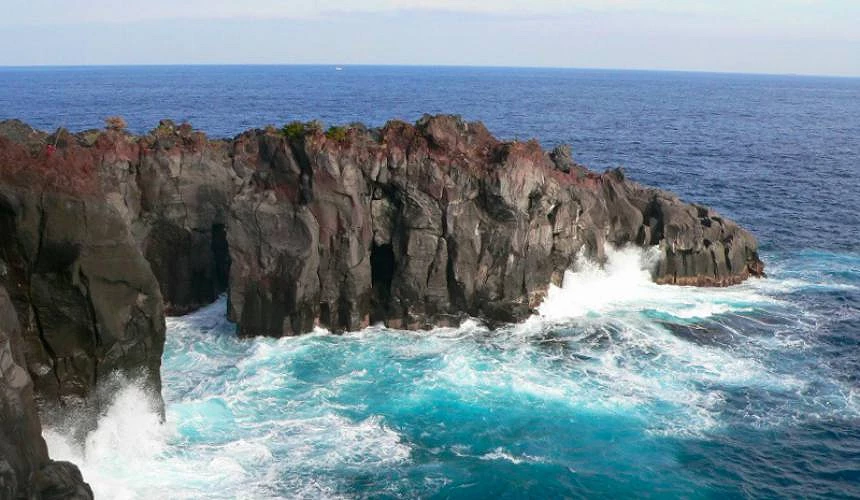 黑色火山岩壁耸立于湛蓝海水中