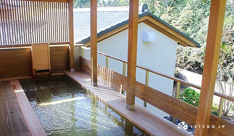 鬼石之湯露天溫泉,木造圍欄與屋頂結構,浴池旁設有扶手