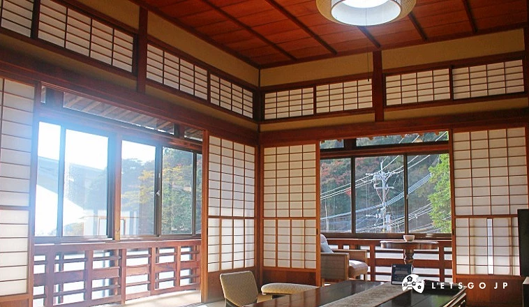 岡本屋旅館和式客房內部,榻榻米地板搭配低矮茶几,障子窗透入自然光