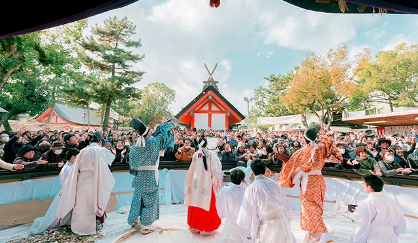 住吉大社境內的初詣儀式,神職人員身著傳統服飾面向大量民眾進行祈福,背景可見神社建築與樹木