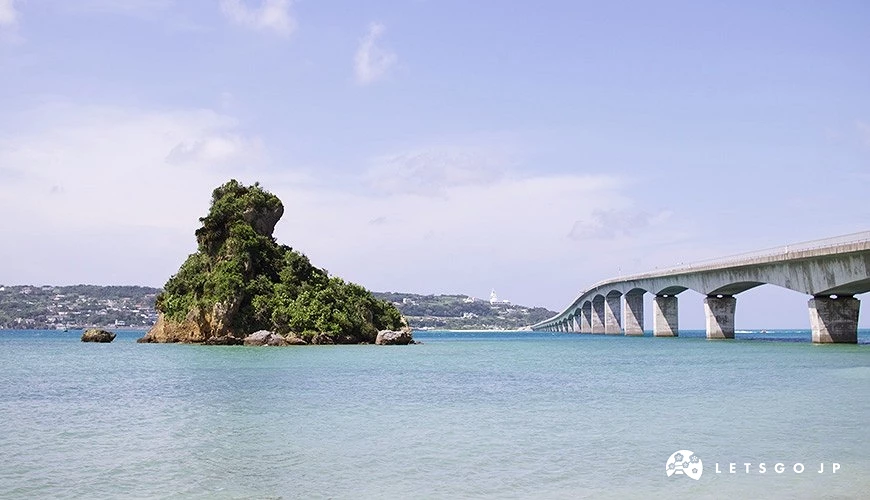 綠樹覆蓋岩島聳立淺海,長橋跨越碧藍海灣連接遠山,風景秀麗寧靜。