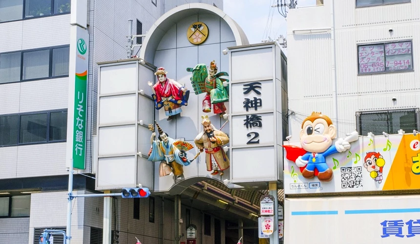 天神桥筋商店街入口标志与牌楼,展示祭典人物装饰与街区招牌