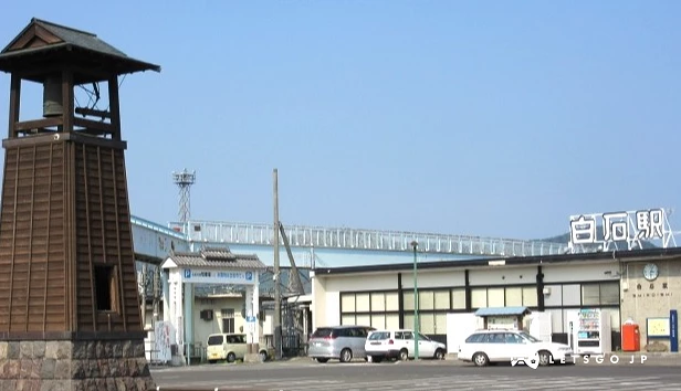 白石站前廣場,站名看板清晰可見,前方設有木造鐘樓型紀念物