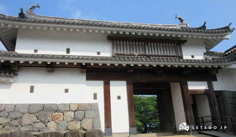 白石城二之門正面,白牆與木構大門,石砌基座