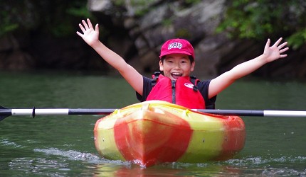 日本關東栃木縣日光市旅遊必去景點推薦小男孩在川治溫泉小網水壩湖面開心地划獨木舟