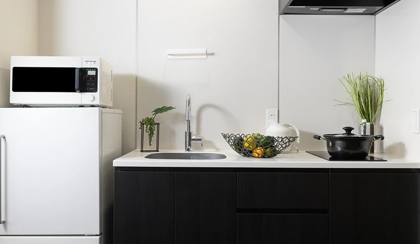 MIMARU 飯店客房廚房設備齊全,可見冰箱、微波爐、洗手台與電磁爐,設計簡約現代,展現公寓式飯店的實用機能