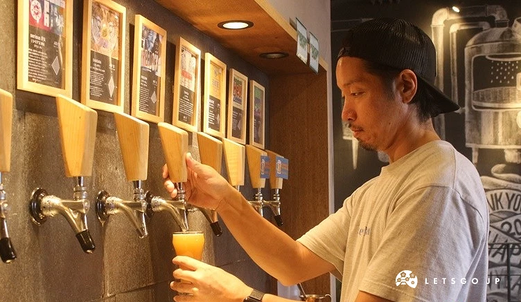 一名男性工作人員正在「Lit work place」的啤酒龍頭前,將現釀精釀啤酒倒入玻璃杯中。