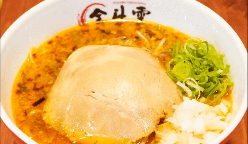 一碗白色碗裝的日式拉麵上面有一片大燒肉碗邊有金斗雲字樣