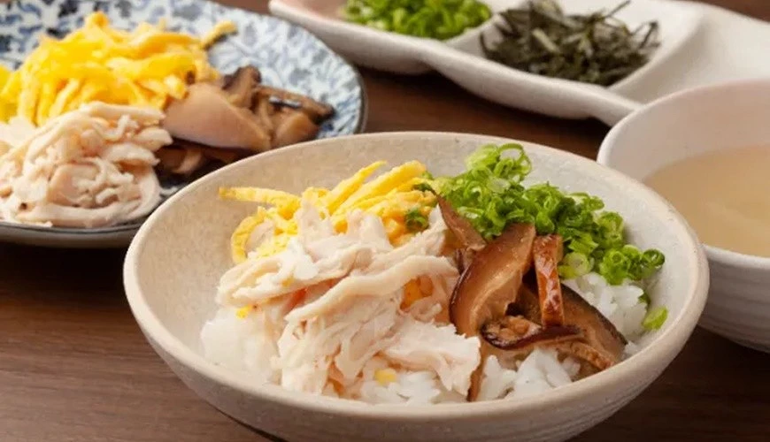 一碗白飯上有雞肉絲及香菇絲及蛋絲和青蔥