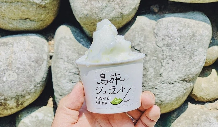 在岩石前面有一隻手拿著一杯紙杯裝的冰淇淋