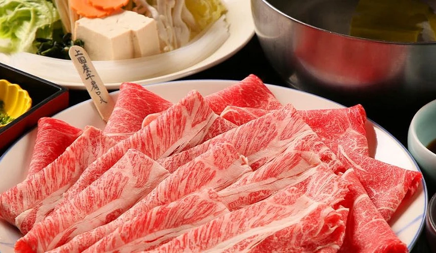 摆满雪花和牛肉片的寿喜烧套餐,搭配豆腐、蔬菜与高汤锅,呈现札幌知名锅物料理的丰盛美味