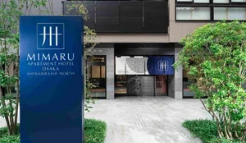 MIMARU 大阪心斋桥 WEST 饭店外观,入口简约雅致,蓝色招牌与绿意盎然的植栽相映成趣。