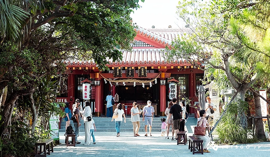波上宫本殿前景,红色琉球风神社建筑,参拜民众进出其间,周围绿树环绕的景象