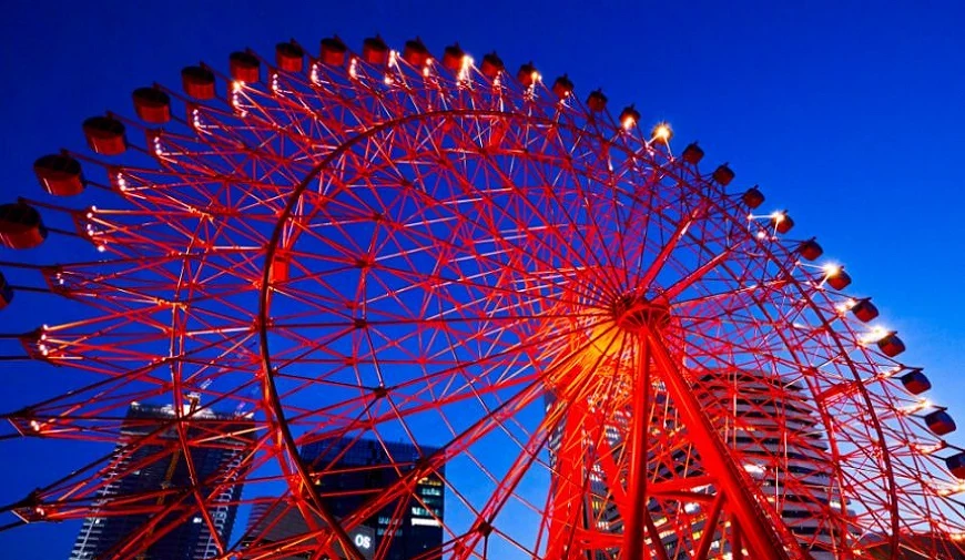 夜晚的 HEP FIVE 红色摩天轮从低角度拍摄,轮架亮起灯光,背景可见梅田高楼的夜景轮廓