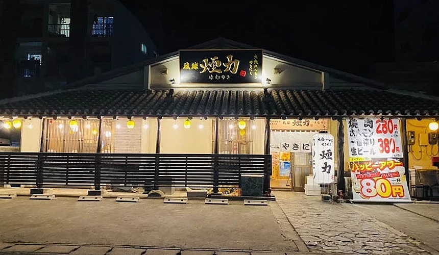 餐廳的外觀建築,上方有黑底金字的「琉球煙力」招牌,門口擺放著優惠看板。