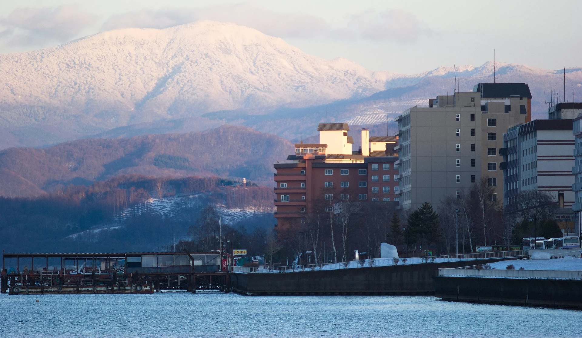 洞爷湖温泉街冬季景色,湖畔饭店林立,背景为覆雪山峦与冬日天空
