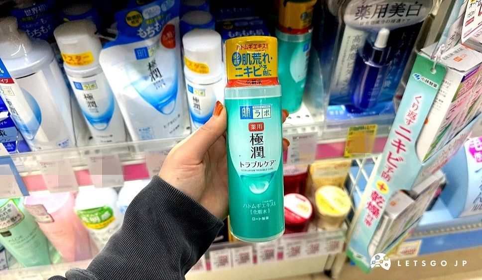 一位女性的手拿着一瓶湖水绿色上面印有极润字样的化妆水商品站在商品架前