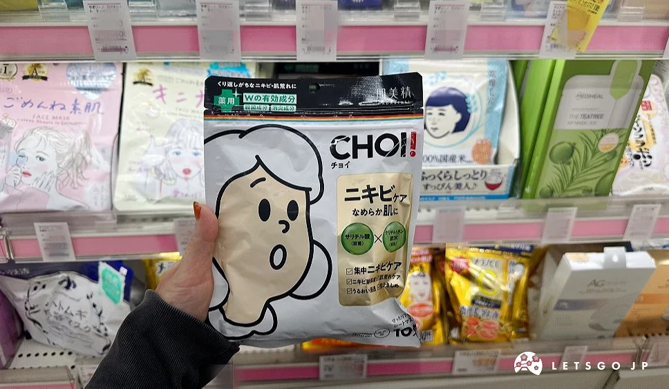 位女性的手拿着一袋白色左边印有一个白发插画女孩右边印有英文CHOI字样的方形商品站在商品架前