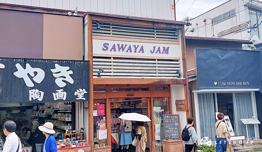 位于旧轻井泽银座通商店街的泽屋果酱 (SAWAYA JAM) 店面,木质调门面挂着紫色招牌,游客正进出参购
