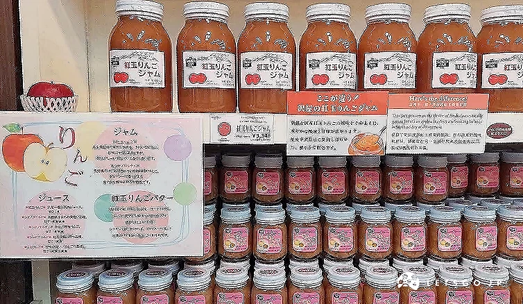 泽屋果酱 (SAWAYA JAM) 的红玉苹果系列专区,上方陈列着大瓶装的红玉苹果果酱,下方则是小瓶装。旁边附有详细的介绍海报,说明红玉苹果果汁、果酱与苹果奶油的风味特色