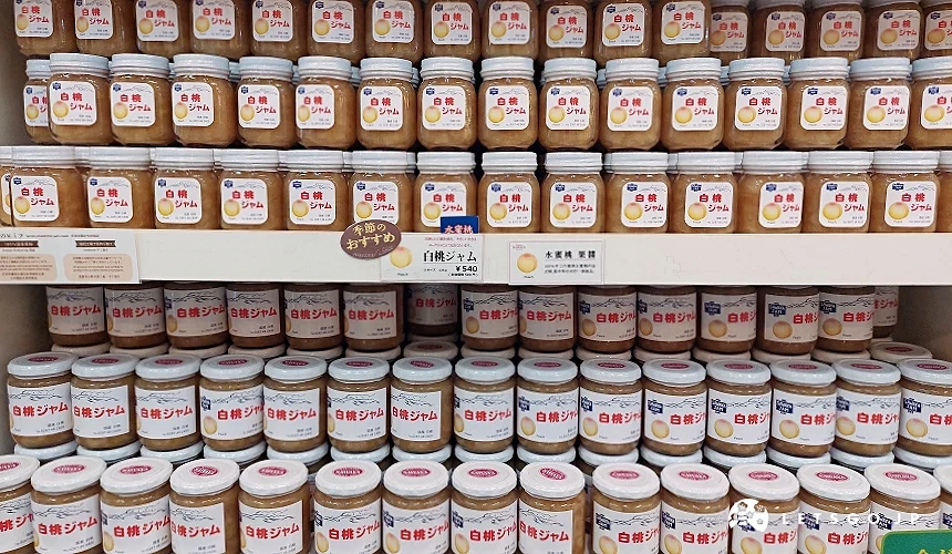 泽屋果酱 (SAWAYA JAM) 店内整齐陈列的白桃果酱货架,透明玻璃瓶装着粉橘色的手工果酱,上方贴有「季节推荐」标示