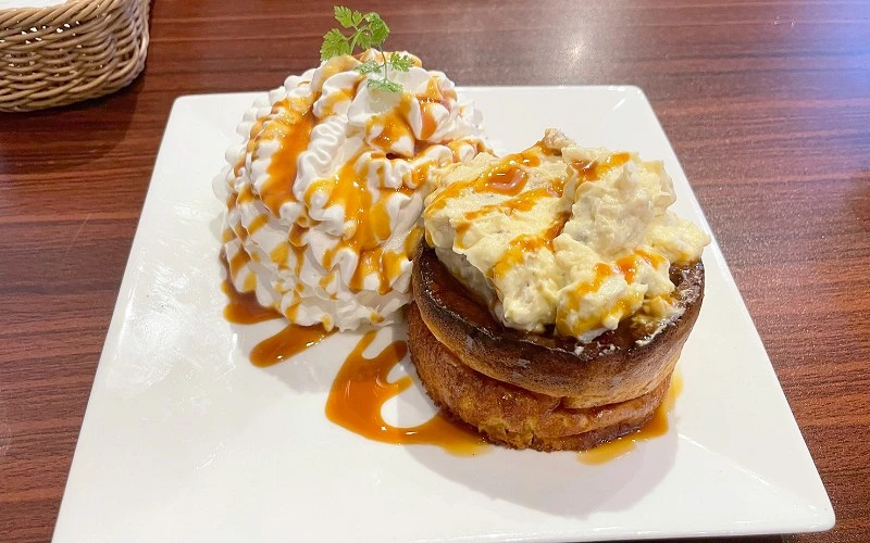 白色盤子上有鬆餅和奶油，搭配橘色醬汁和綠色葉子裝飾