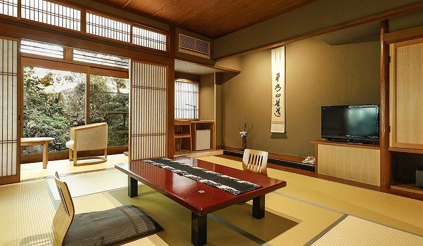 城崎山本屋和式客房里叠叠米上有红色桌子及可靠背的椅垫典雅且从房间可欣赏绿意