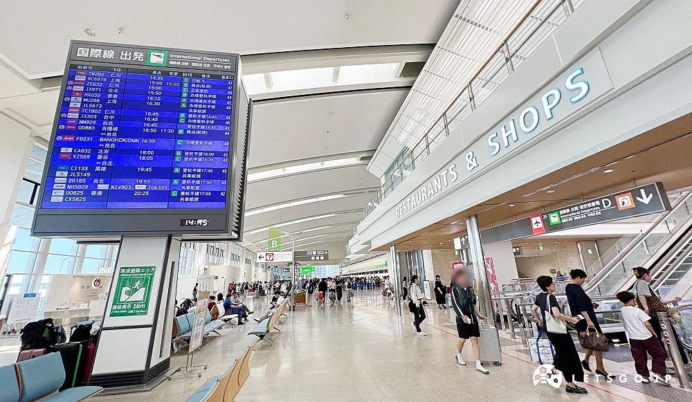 那霸机场国际线出境大厅,显示航班资讯看板与旅客排队通关,旁为餐厅与商店区域