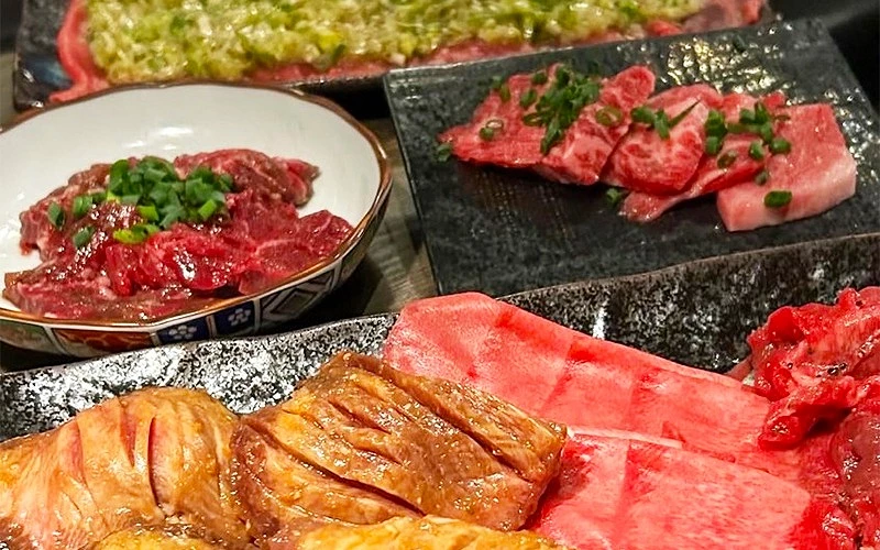 桌上擺放多盤生牛肉和牛舌，撒有蔥花調味
