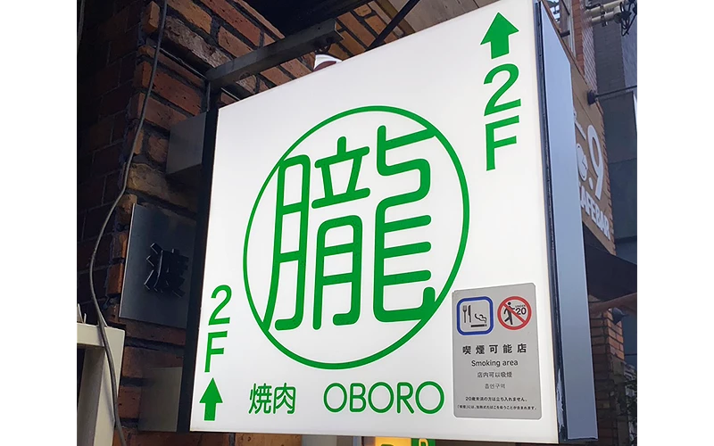 白色招牌寫著綠色的「朧」字和2F，下方標示燒肉OBORO