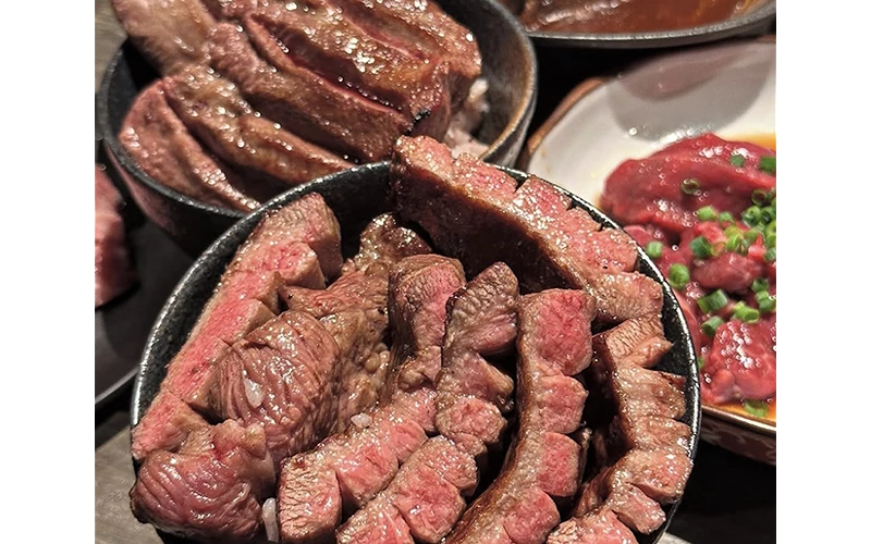 碗裡盛裝烤好的牛肉塊，旁邊有生牛肉片