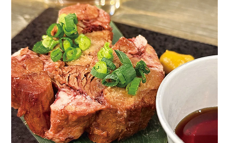 盤子上擺放厚切牛舌撒蔥花，旁邊有醬料碗