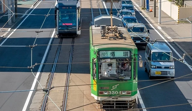 札幌大馬路上,綠色路面電車和小客車行駛著