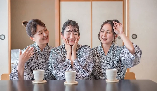 三位身穿浴衣剛泡完湯的女子,用手扇風擦汗一副很熱的樣子