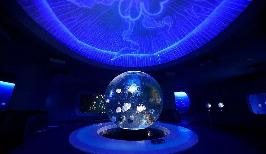 昏暗的空間裡,中間有一顆透明大球,上方有藍色打光