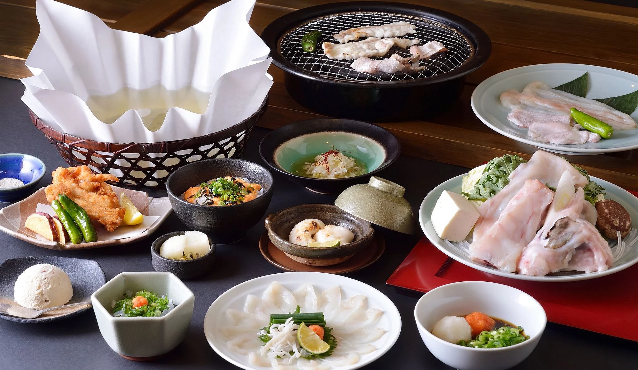 餐桌上擺放著多道菜品,有一盤生魚片、一盤鍋物用河豚生肉、炸河豚、豆腐,還有甜點冰淇淋