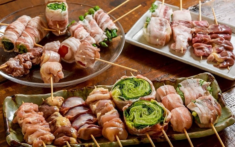 多盤串燒食材擺盤，有培根蔬菜卷、雞肉串與內臟串