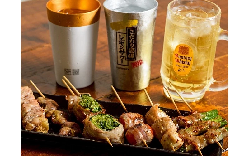 串燒肉串擺放在黑色長盤中，搭配三杯含冰飲品，其中一杯印有 Suntory Whisky 標誌