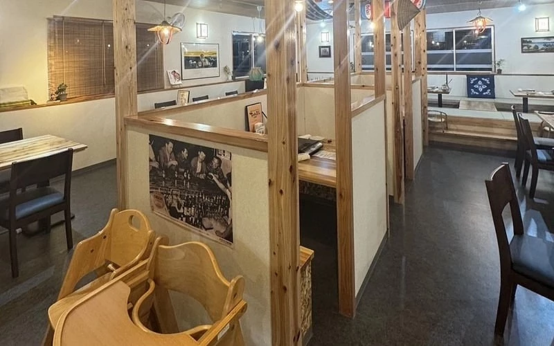 餐廳內部木質隔間座位，前景放有兒童座椅