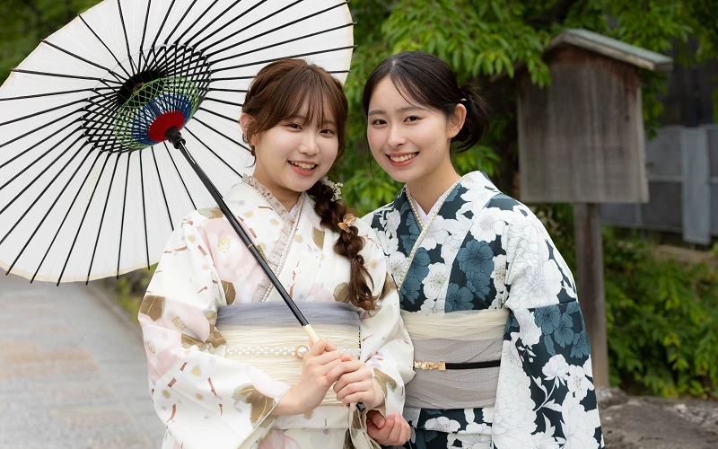 兩位女性穿著和服，其中左邊的女性拿著紙傘