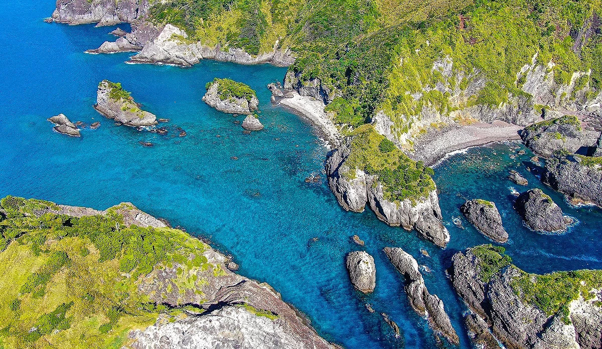 绿色山脉和岩石中间,有蓝色海洋