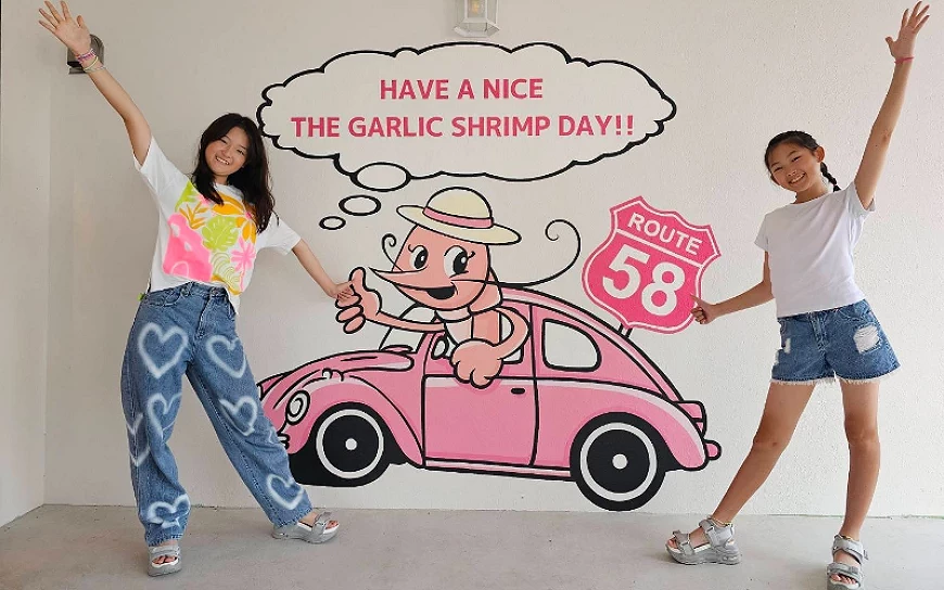 沖繩恩納村「THE GARLIC SHRIMP」店舖牆壁塗鴉前兩名女性正在打卡留念