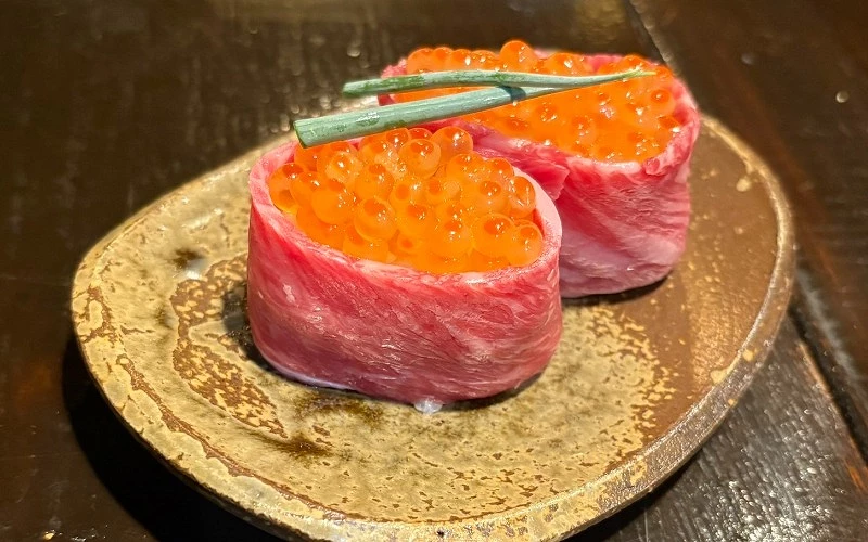 牛肉包覆鮭魚卵握壽司兩貫，上方放置蔥段裝飾