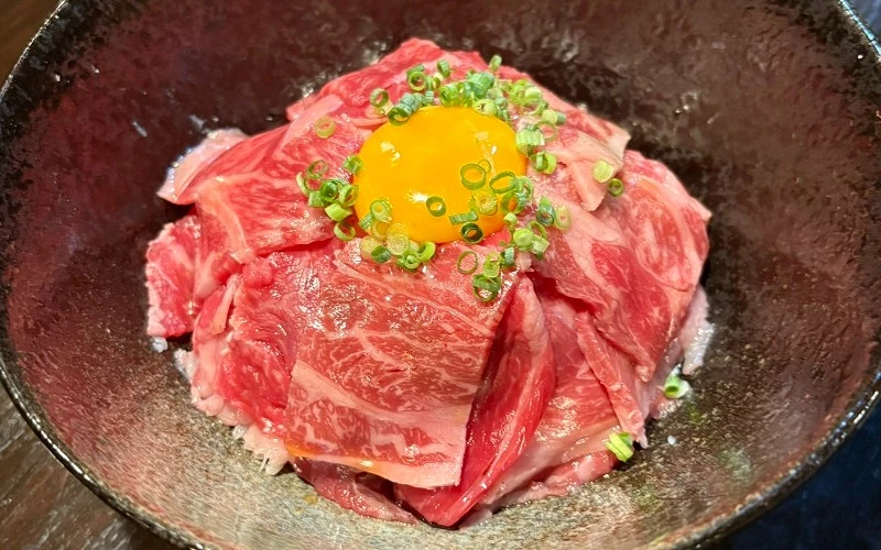 生牛肉片蓋飯，上面放有生蛋黃與蔥花