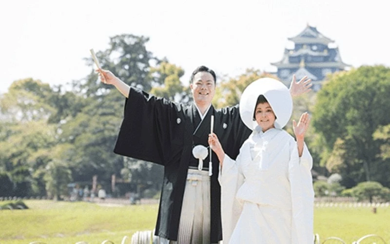 一對身穿和服與白無垢的新婚夫婦在城堡前合影