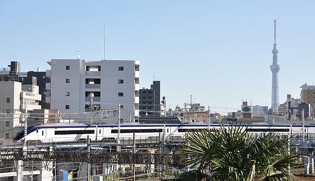 京成電鐵 Skyliner 行駛在東京市區鐵道上,遠方可見東京晴空塔