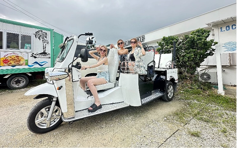 三位女性乘坐一輛白色三輪車